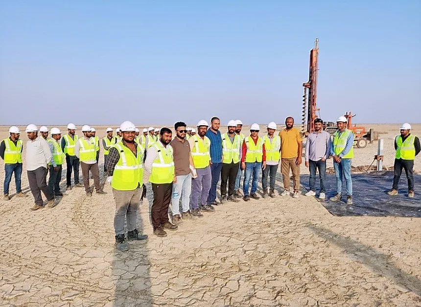 The piling crew with a tractor-mounted auger rig behind them
