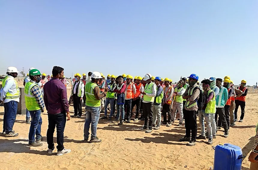 Toolbox talk with the day crew — high-visibility vests and helmets mandatory on every block
